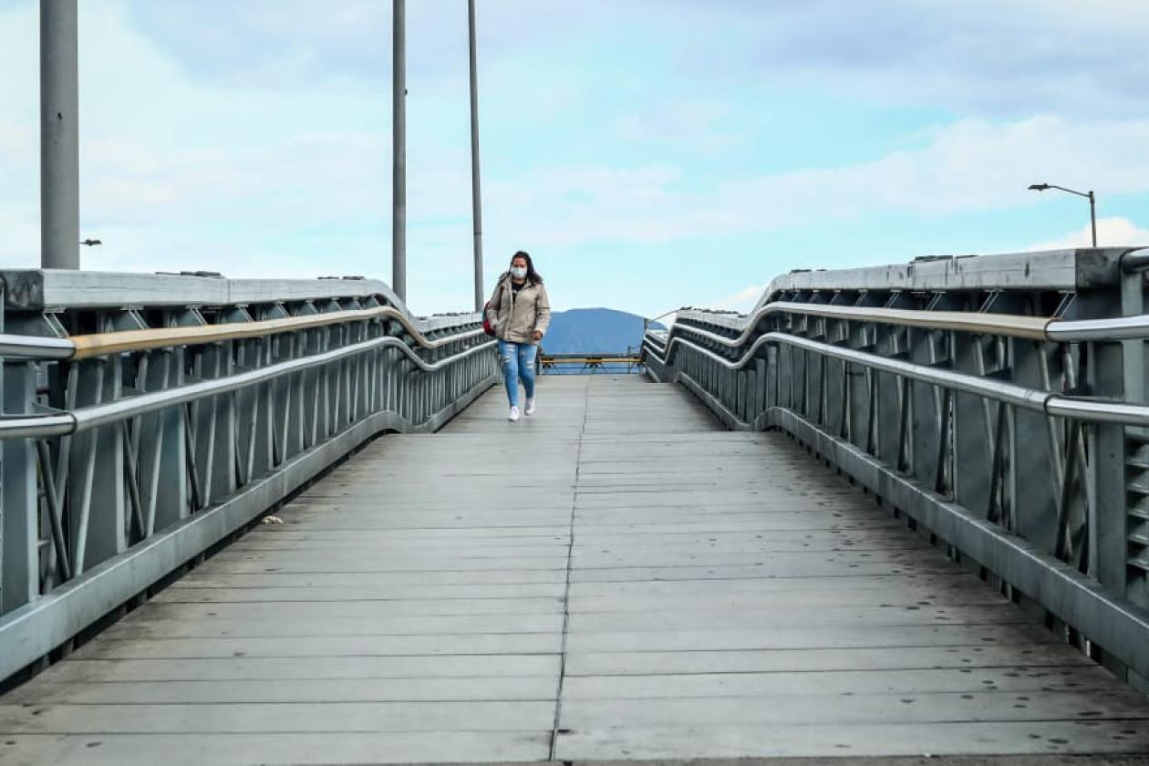 Fotografía de una persona caminando en un puente peatonal.d