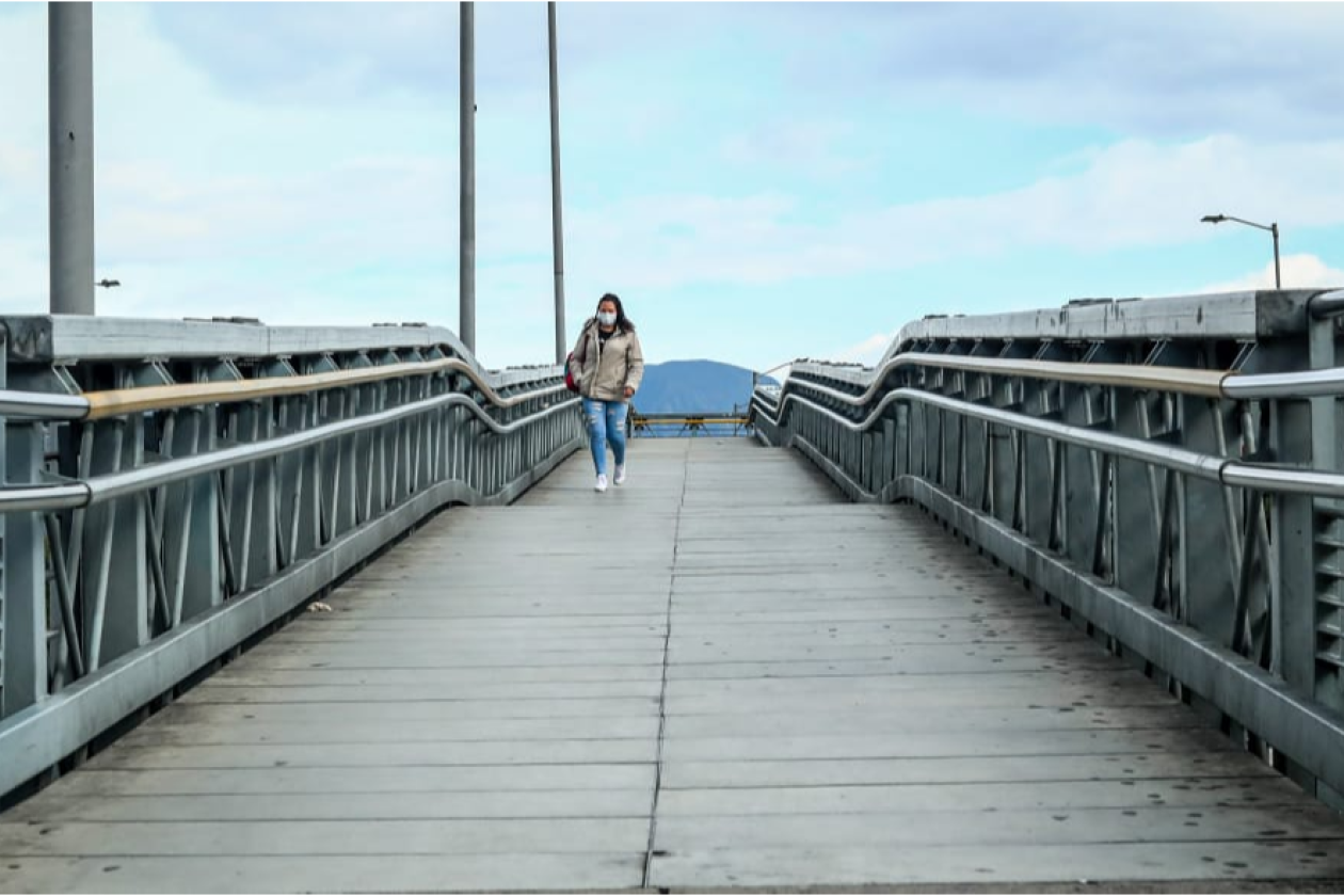 Fotografía de una persona caminando en un puente peatonal.