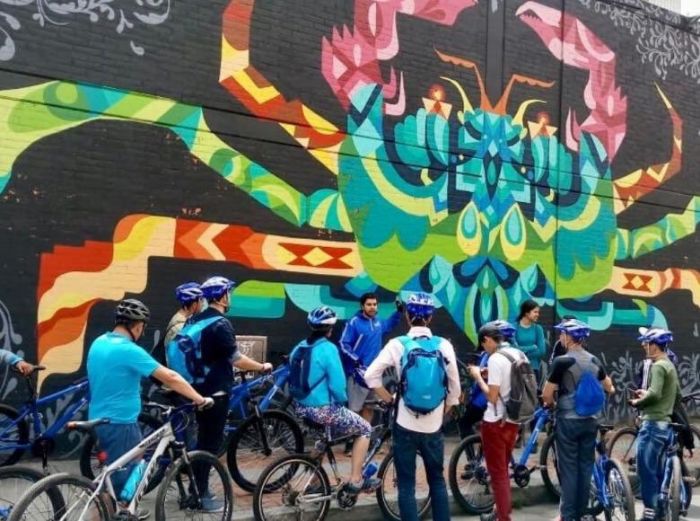 Un grupo de ciclistas visitan un graffiti en Bogotá.