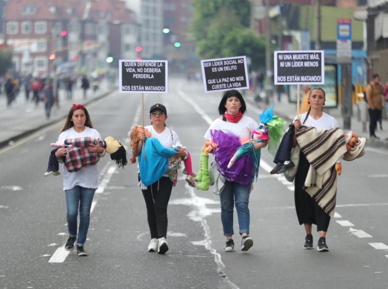 Mujeres cargando muñecos de trapo entre sus brazos