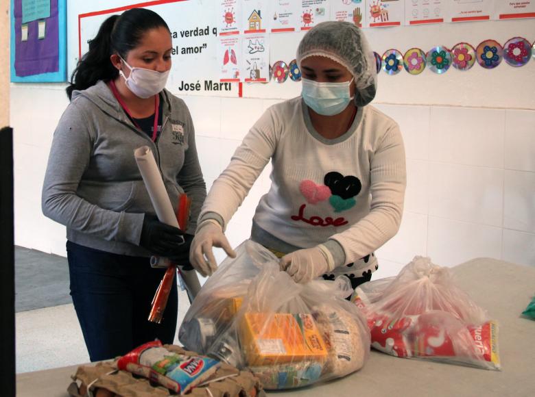 Funcionaria entregando un mercado a una beneficiaria.