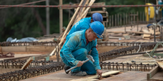 Un trabajador del Acueducto de Bogotá, martillando algunas tablas de madera 
