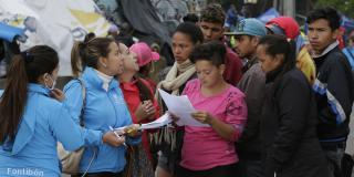 Dos funcionarias de la Alcaldía atendiendo a un grupo de personas, migrantes en el Centro Integral de Atención al Migrant