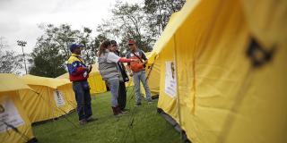 Varias personas en el campamento para venezolanos en Bogotá atendiendo y resolviendo inquietudes de esta población 