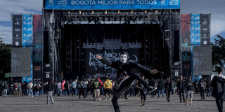 Un joven luce una máscara mientras da un salto delante del escenario principal de Rock al Parque en el Parque Simón Bolívar.