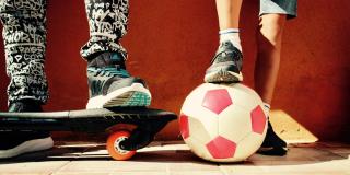 Imagen de los pies de jóvenes con un balón de fútbol y una patineta 