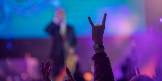 Un hombre alza su mano haciendo una señal en medio de una presentación de Rock al Parque 2019.