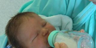 Imagen de un bebé tomando leche en biberón 