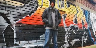 Ricardo Acosta posa frente a una pared pintada con un graffiti.