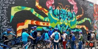 Un grupo de ciclistas visitan un graffiti en Bogotá.