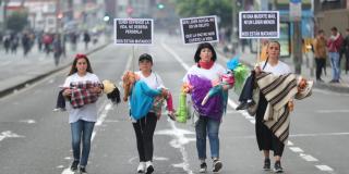 Mujeres marchan con muñecos de trapo entre sus brazos, representan a líderes sociales asesinados.