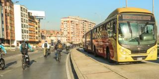fotografía de ciclistas rodando al lado de un bus de TransMilenio