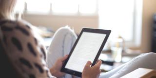 Imagen de una mujer leyendo en una tablet.