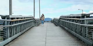 Fotografía de una persona caminando en un puente peatonal.d