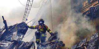 Imagen de un bombero saliendo del humo de un incendio.