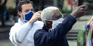 Secretario de Gobierno poniéndole mascarilla a un ciudadano.
