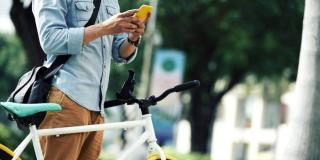 Imagen de una persona en bicicleta con su celular.