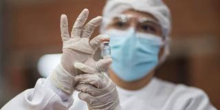 Imagen de una enfermera con un biológico en su mano.