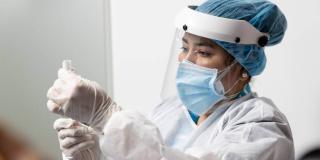 Imagen de una funcionaria de salud con un biológico en su mano.