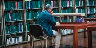 Hombre leyendo un una biblioteca
