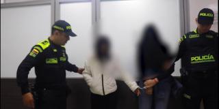Dos mujeres siendo presentadas en captura por dos policias