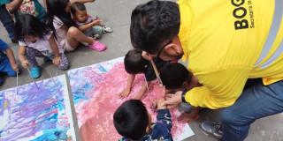 Imagen de un funcionario de Integración Social ayudando a niños y niñas Emberá a pintar.