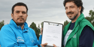 Imagen de dos funcionarios sosteniendo el documento del convenio para la protección animal.