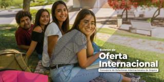 Jóvenes en un campus universitario sentados en una zona verde.