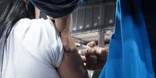 Foto que muestra una mano de una enfermera con una jeringa 