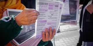 En la foto una señora mostrando y entregando un volante sobre la Ruta Única de Atención en las URI de Bogotá