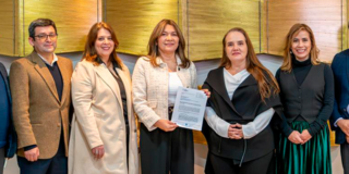 Imagen de varias personas con un documento y posando para la foto