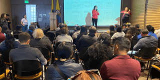 Foto de una mujer hablando en un auditorio 