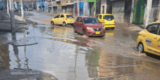 Foto de unos carros al lado de un charco de agua en Bogotá 