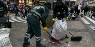Foto que muestra dos trabajadores de la UAESP levantando basura de las calles