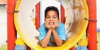 Imagen de un niño sonriendo con las manos en la cara