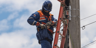 Imagen de técnico de ENEL Codensa subido en una escalera revisando un poste de luz