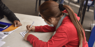 Imagen de una mujer firmando una hoja