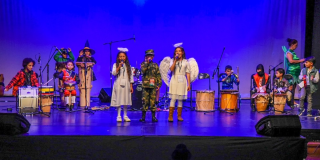 Imagen de niños y niñas cantando disfrazados en una tarima