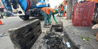 Foto que muestra un trabajador del Acueducto de Bogotá limpiando una alcantarilla