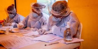 Foto que muestra personas con guantes y tapabocas sentados en una mesa