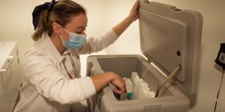 Foto que muestra una enfermera revisando un recipiente con vacunas 