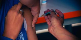 Foto que muestra una persona que le están colocando una vacuna en su brazo