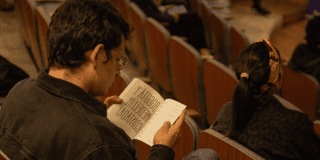 Imagen de un hombre joven sentado leyendo un libro