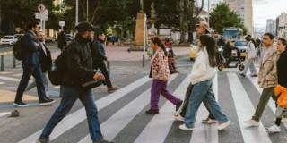 Foto de distintos peatones pasando por una vía de Bogotá