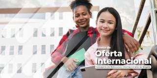 Foto de dos jóvenes sonriendo y al fondo un edificio universitario.