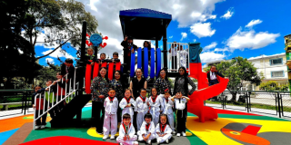 Foto de un grupo de niños y adultos disfruta un colorido parque infantil recién renovado bajo un cielo despejado