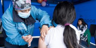 Imagen de una enfermera que vacuna a una niña sentada