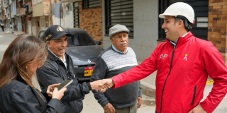 Un funcionario dialoga y estrecha la mano a vecinos del barrio mientras recorren las obras viales en la zona.