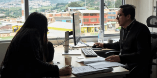 Imagen de dos personas en una oficina en medio de un computador