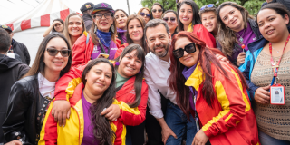Foto de un grupo de mujeres y un funcionario sonríen juntos durante una jornada comunitaria.